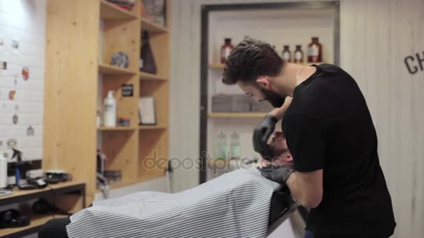 Парикмахер расчесывает бороду клиента и танцует в парикмахерской . — стоковое видео