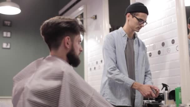 Friseur fügt etwas Wachs zum Kämmen des Kunden hinzu. — Stockvideo