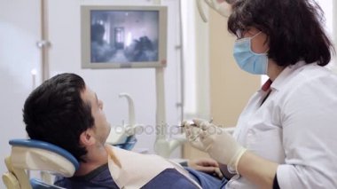 Diş hekimi diş erkek hasta tarafından diş ayna denetler.