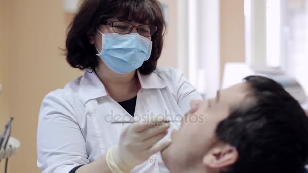 Dentysta sprawdza zęby pacjenta przez lusterko dentystyczne — Wideo stockowe