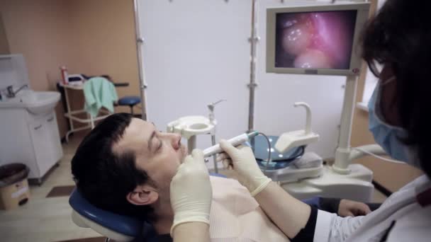 Zahnarzt untersucht den Mund eines Patienten mit einer Intraoralkamera. — Stockvideo