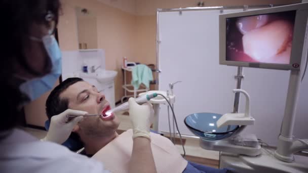 Dentista examinando la boca de un paciente con una cámara intraoral . — Vídeos de Stock