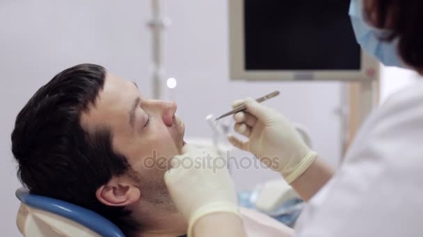 牙医把附近的病人牙齿的棉花球. — 图库视频影像