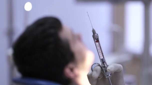 Detailní záběr z injekční stříkačky s lékem uvnitř a rozostření pacienta na pozadí. — Stock video
