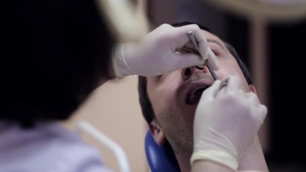 Zubař klade vatový tampon poblíž zub pacientů. — Stock video