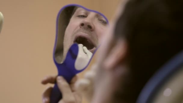 Dentista femenina mostrando un diente con problemas para ella mirando a un paciente espejo . — Vídeos de Stock