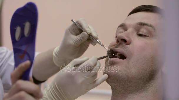 Dentista feminina mostrando um dente com problemas para ela olhando para um paciente espelho . — Vídeo de Stock