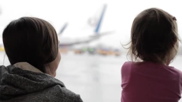 Мать и маленькая дочь смотрят в окно терминала аэропорта — стоковое видео