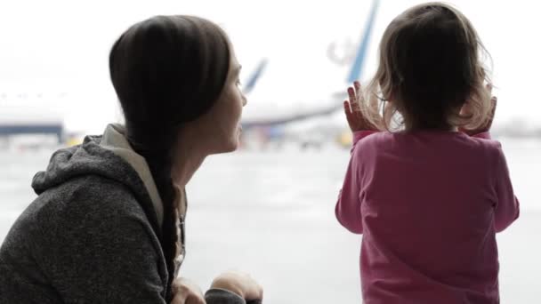 Mama i córeczka patrząc przez okno na lotnisku — Wideo stockowe
