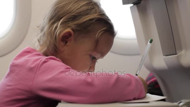 Liten flicka sitter med Skrivbok på flygplan. — Stockvideo