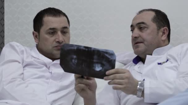 Close-up van twee artsen praten met x-ray prints — Stockvideo