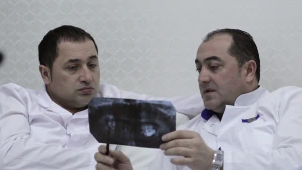 Крупный план двух врачей, говорящих с рентгеновскими отпечатками — стоковое видео
