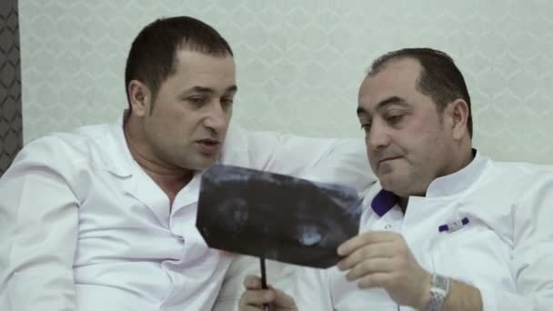 Zbliżenie: dwóch lekarzy rozmawia z x-ray drukuje — Wideo stockowe