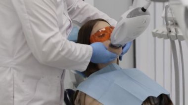 Doktor güzel bir genç kadın lazer beyazlatma dişler yordamı için hazırlanıyor.