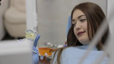 Hasta ile konuşmak ve bir model diş gösteren diş hekimi.