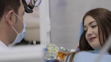 Hasta ile konuşmak ve bir model diş gösteren diş hekimi.