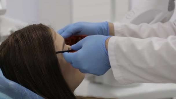 Médico preparando a una hermosa mujer joven para el blanqueamiento láser procedimiento de dientes . — Vídeos de Stock