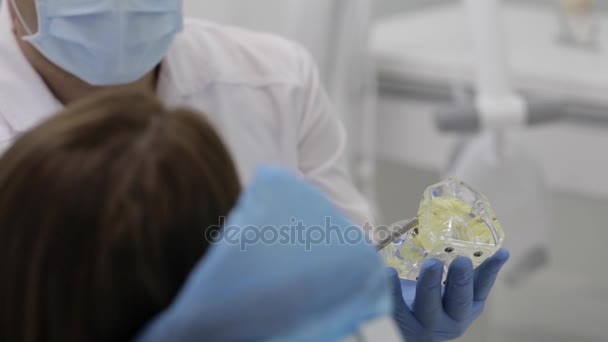 Dentista hablando con el paciente y mostrando un modelo de dientes . — Vídeos de Stock