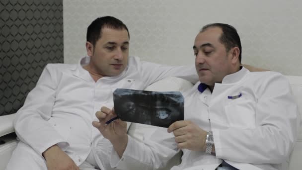 Два дантиста разговаривают с рентгеновскими снимками — стоковое видео