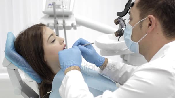 El dentista hace el procedimiento. Mujer joven Beutyful visitar una clínica dental moderna . — Vídeos de Stock