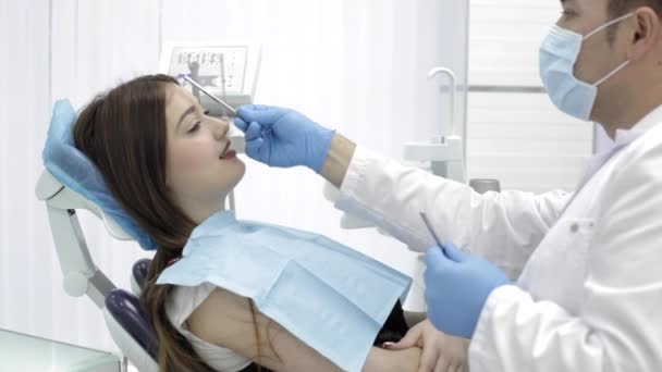 Médico en un consultorio de dentistas está preparando al paciente para el procedimiento . — Vídeos de Stock