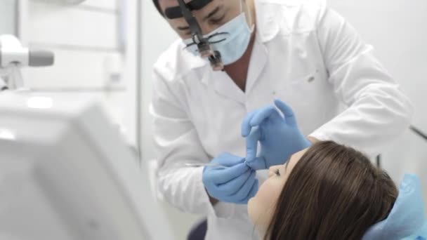 El dentista hace el procedimiento. Mujer joven Beutyful visitar una clínica dental moderna . — Vídeos de Stock