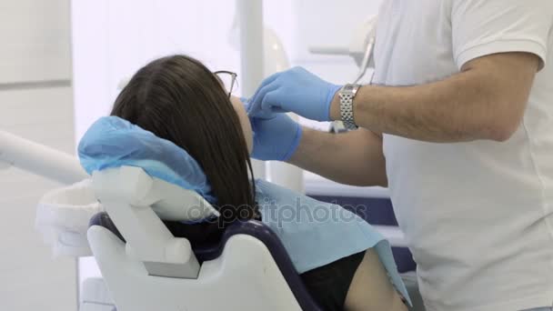 Male dentist making procedure on young female patient at modern clinic — Stock Video