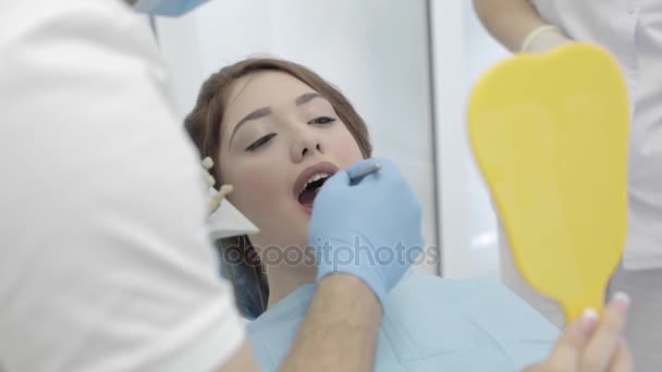 Vrouw bezoek tandheelkundige kliniek. Tandarts controleren en selecteer de kleur van de tanden. — Stockvideo