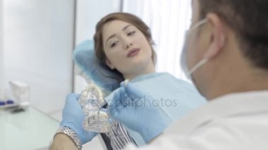 Bayan hasta için çene modeli gösteren diş hekimi