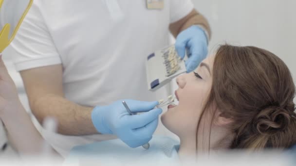 Frauen besuchen Zahnklinik. Zahnarzt checken und die Farbe der Zähne auswählen. — Stockvideo