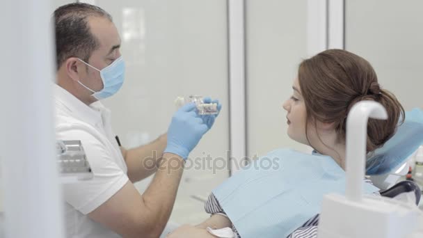 Dentista demostrando modelo de mandíbula a paciente femenina — Vídeos de Stock