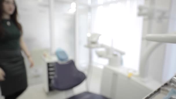 Zubní zařízení a pacientka sedí na židli zubař na pozadí — Stock video