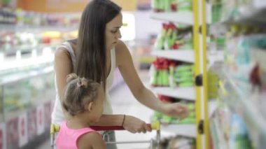 Sevimli kızı bakkal alışveriş merkezinde bir bitkisel yağ seçimi ile genç kadın