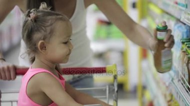 Sevimli kızı bakkal alışveriş merkezinde bir sos seçimi ile genç kadın