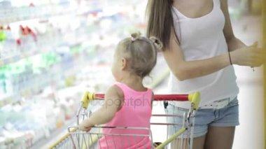 Kız bebek toddler içinde oturan zaman annesi süpermarkette ürünler seçme