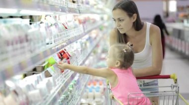 Sevimli kızı bakkal alışveriş merkezinde bir yoğurt seçimi ile genç kadın