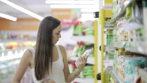 Mujer joven con linda hija eligiendo una mercancía en el centro comercial de comestibles — Vídeo de stock