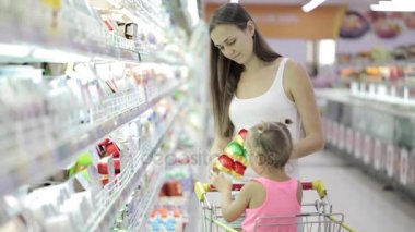 Sevimli kızı bakkal alışveriş merkezinde bir yoğurt seçimi ile genç kadın