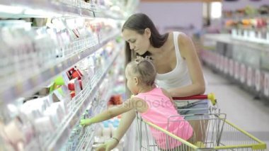 Sevimli kızı bakkal alışveriş merkezinde bir yoğurt seçimi ile genç kadın