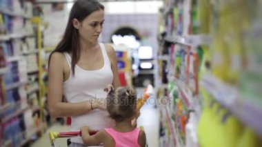 Deterjanlar, süpermarket evinde için seçme küçük kızı olan genç kadın