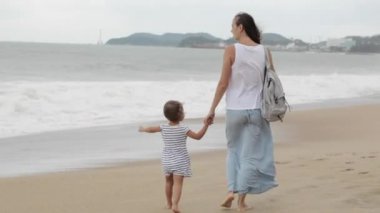 Küçük kızı kötü havada deniz boyunca yürüyüş ile anne