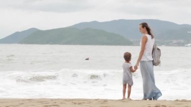 Küçük kızı kötü havada deniz boyunca yürüyüş ile anne