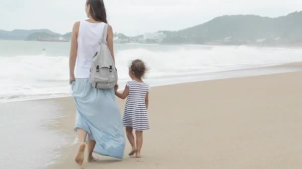 Mère avec sa petite fille marchant le long de la mer par mauvais temps — Video