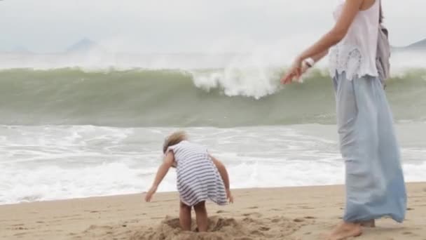 Mutter mit kleiner Tochter läuft bei schlechtem Wetter am Meer entlang — Stockvideo