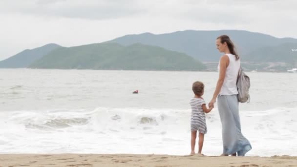 Madre con hija pequeña caminando por el mar con mal tiempo — Vídeos de Stock