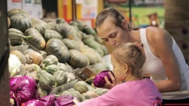 Seçme sebze süpermarket arabası içinde küçük kızı ile genç anne