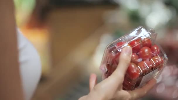 Mladá matka s malou dcerou v vozík vybírání rajčata v supermarketu — Stock video