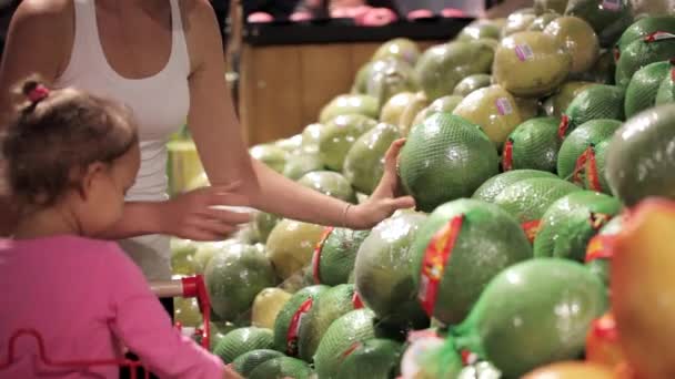 Junge Familie mit Mutter und kleiner Tochter wählt Pomelo im Supermarkt. — Stockvideo