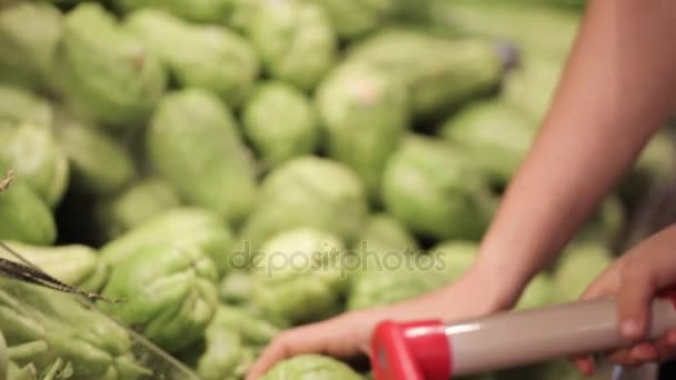 Família jovem de mãe e filha pequena escolhendo legumes no supermercado . — Vídeo de Stock
