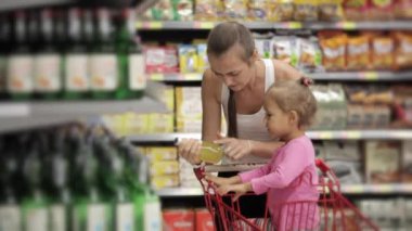 Bir içki süpermarket seçme bebek kızı çekici genç kadın.